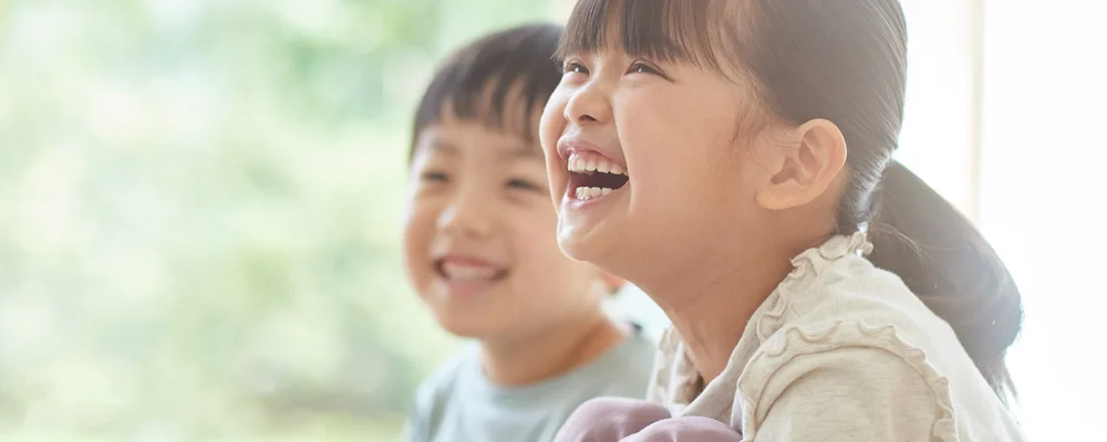 生え変わり期の歯を見せて笑い合う子どもたち｜マルイ錦糸町シティデンタルクリニック