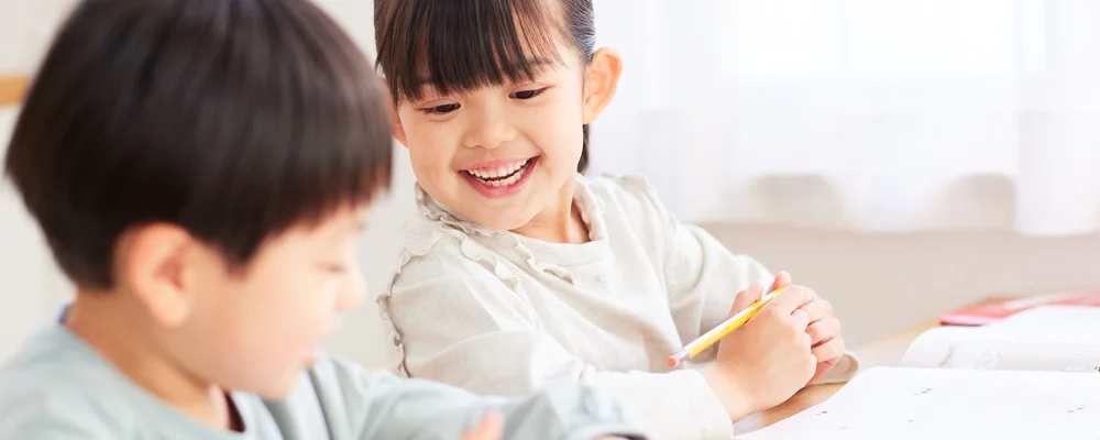 宿題をしながら笑顔を見せる生え変わり期の子ども｜マルイ錦糸町シティデンタルクリニック